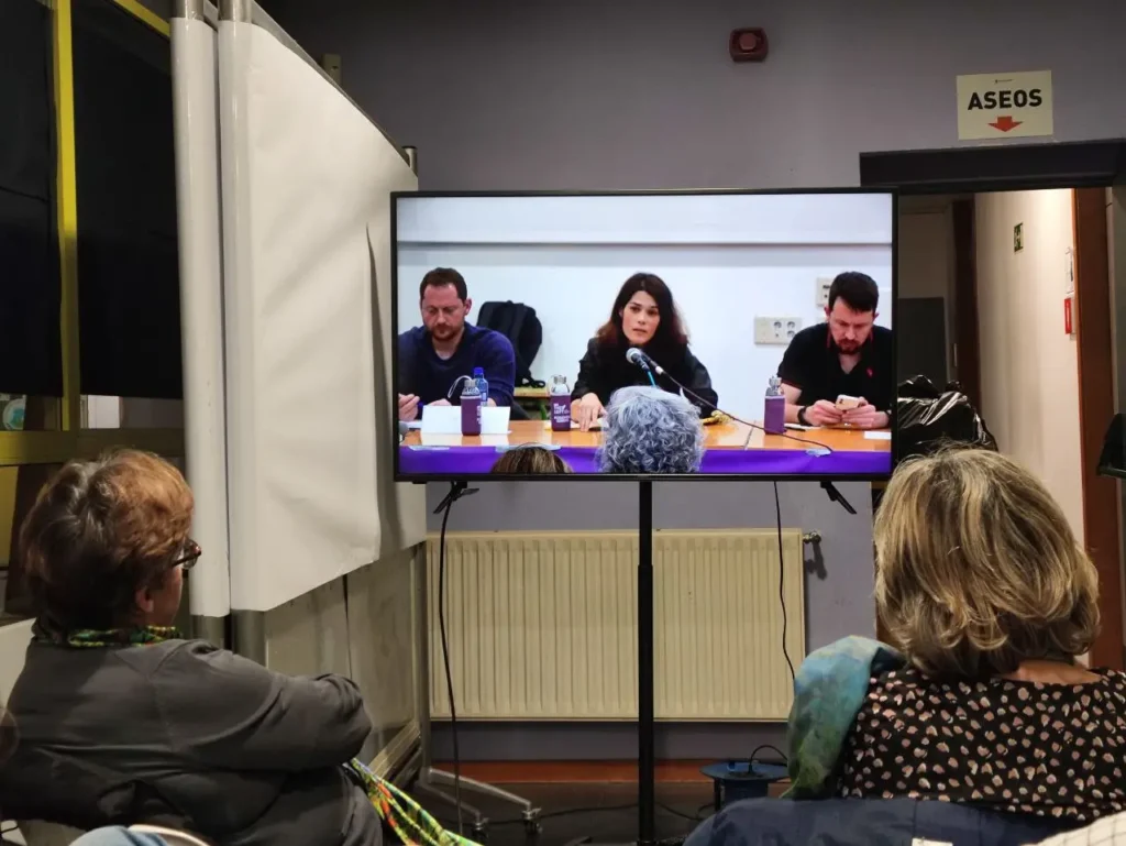 El llenazo de la Casa de Asociaciones obligó a poner una televisión en el rincón anexo para escuchar a Pablo Iglesias y a su equipo jurídico.