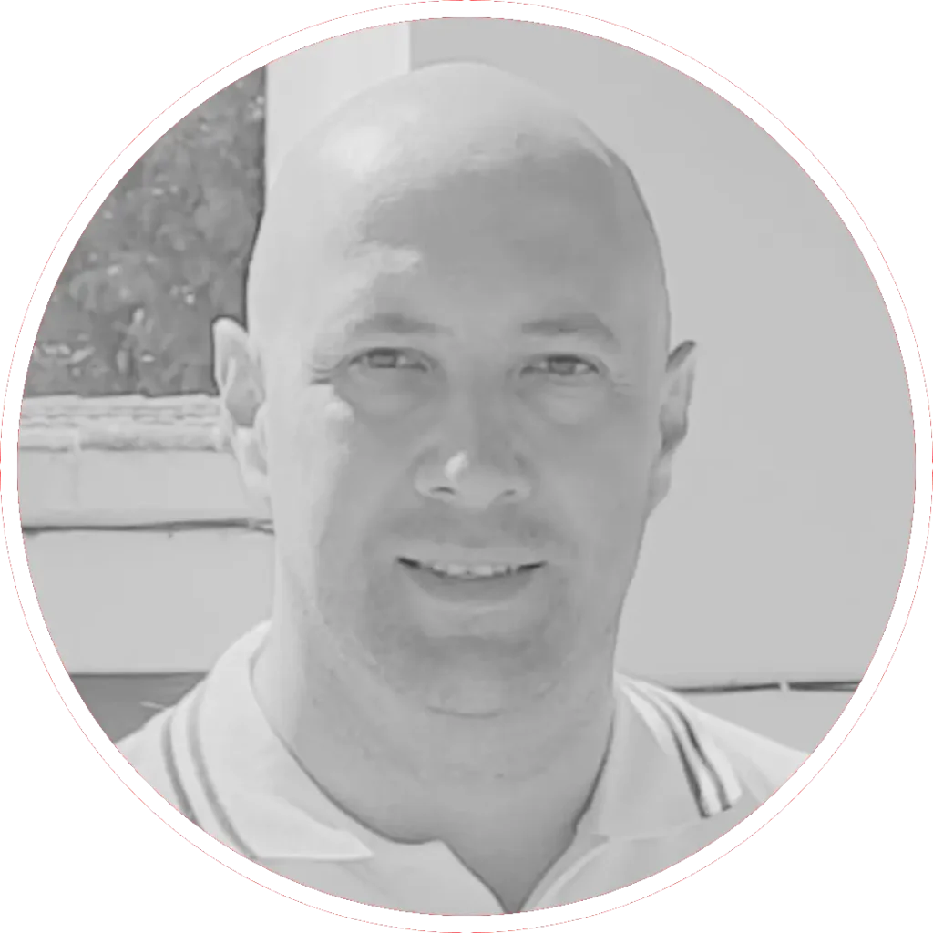 Carlos García Torrijos, un hombre con la cabeza rapada, sonríe ligeramente a la cámara. Lleva una camisa con cuello y está fotografiado en blanco y negro, con un borde circular alrededor de la imagen.