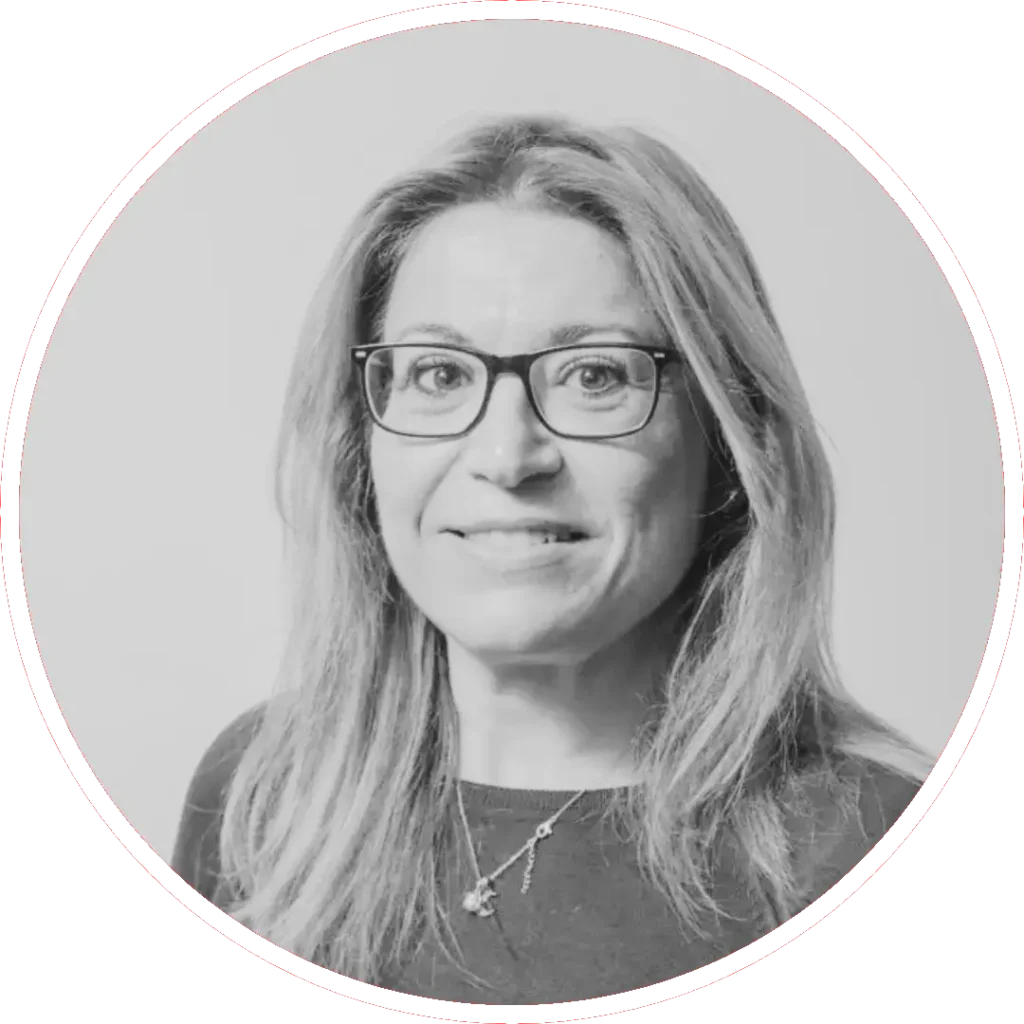 Ruth Quipo Rojas. PSOE. Una mujer de pelo largo y claro y gafas, con un top oscuro y un collar, mira a la cámara con una leve sonrisa. La foto en blanco y negro, enmarcada por un borde circular, insinúa historias de vida tras su expresión tranquila.