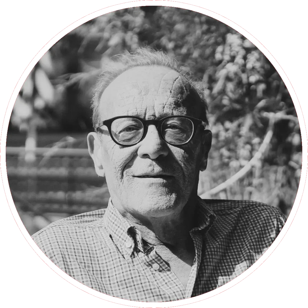 Retrato en blanco y negro de una persona mayor con gafas y camisa a cuadros, mirando a la cámara. Los árboles y la luz del sol crean un fondo moteado. La imagen está enmarcada por un borde circular pixelado.