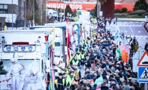 Una gran multitud se agolpa en una calle de Rivas llena de carrozas decoradas y gente disfrazada durante el desfile de la Cabalgata de Reyes. Muchos asistentes llevan abrigos y personal de seguridad con chalecos amarillos recorre el trayecto.