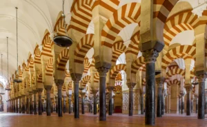 Vista interior de la Mezquita-Catedral de Córdoba que muestra hileras de columnas de piedra y arcos dobles con dovelas rojas y blancas alternadas bajo altos techos abovedados, un ejemplo de renombre entre los bienes inmatriculados.