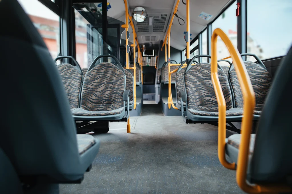 El interior de un autobús urbano vacío con asientos de tela estampada, pasamanos amarillos y grandes ventanillas recuerda a muchos autobuses interurbanos. El pasillo despejado deja espacio para los pasajeros y su equipaje, dependiendo de lo que se pueda llevar durante el trayecto.