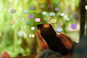 Una persona sostiene en la mano un teléfono, rodeado de representaciones de mensajes de redes sociales | Foto de 123RF/Antstang