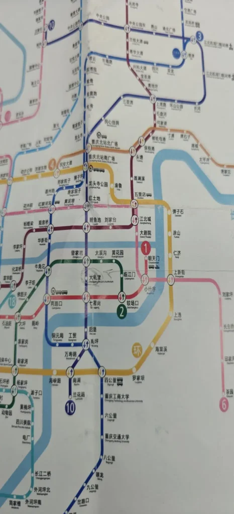 Primer plano de un plano de metro con varias líneas de colores, nombres de estaciones en caracteres chinos y marcadores circulares de intercambiadores y paradas. Las líneas se cruzan y corren paralelas en varios lugares, incluidas las rutas a Chongqing.