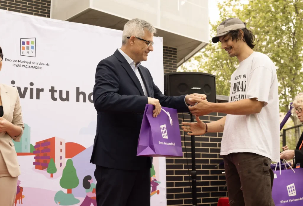 Un joven recibe las llaves de su nueva casa de manos del secretario de Estado de Vivienda, David Lucas, en el acto de entrega de las 83 viviendas celebrado por el Ayuntamiento de Rivas.