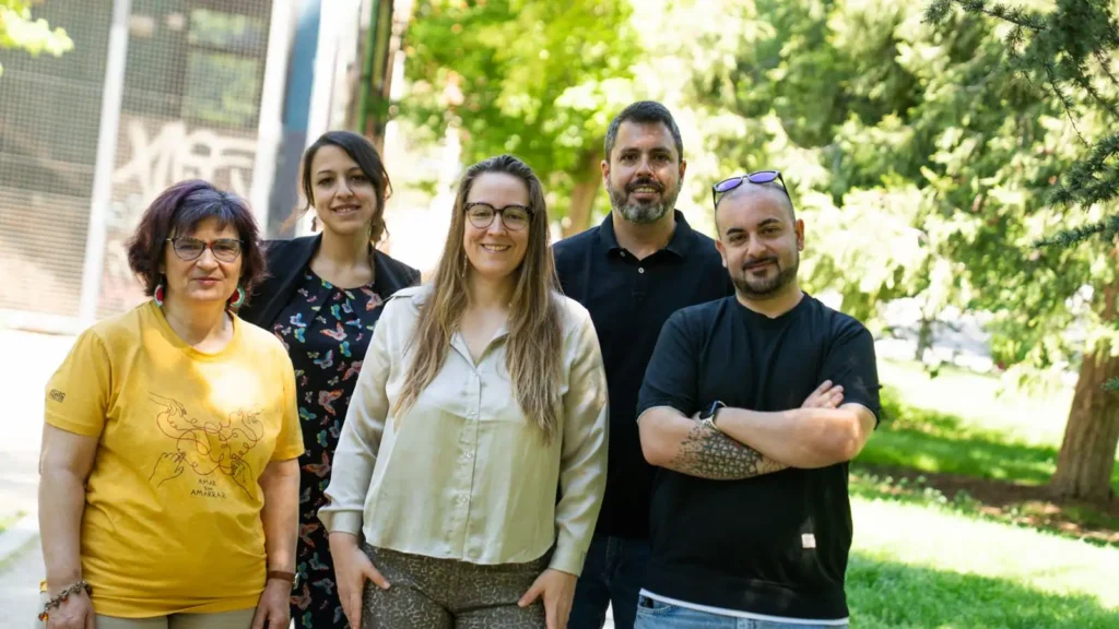 Cinco adultos posan al aire libre frente a unos árboles verdes para una foto de grupo. Representan a la Asociación Vecinal Covibar, visten informalmente y sonríen a la cámara tras hablar de las últimas mejoras del barrio.
