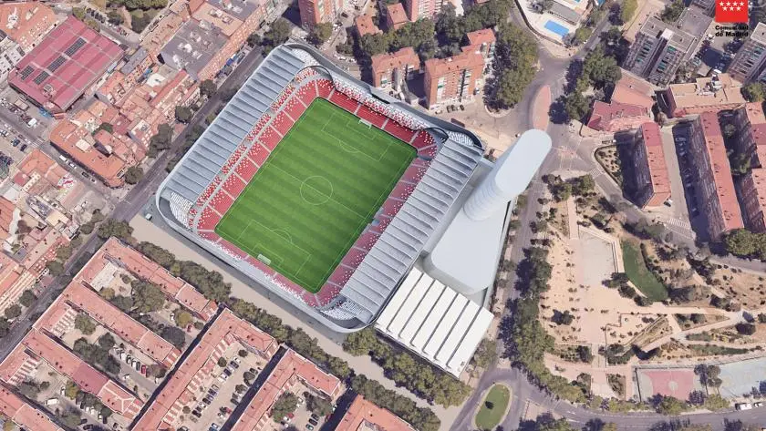 Vista aérea del Estadio de Vallecas, con las gradas rojas y blancas, rodeado de edificios de la ciudad, carreteras y una zona verde cercana con árboles. Está previsto que el estadio sea objeto de una reforma valorada en 60 millones.