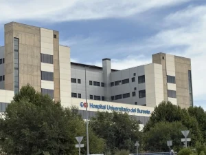 Un edificio hospitalario grande y moderno, con fachadas de color beige y blanco, numerosas ventanas y un letrero en el que se lee «Hospital Universitario del Sureste» —visible en parte tras los árboles verdes bajo un cielo parcialmente nublado—, parece utilizarse tanto para la atención a los pacientes como para tareas administrativas, como el «borrador automático».