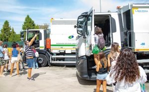 Una niña sube a la cabina de un camión de recogida de residuos de Rivamadrid mientras varias familias esperan su turno en la jornada de puertas abiertas