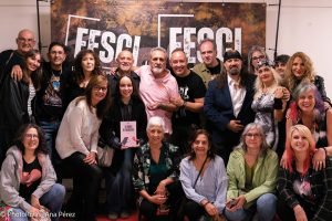 Una veintena de personas participantes del Festival de Cine Independiente (FESCI) posa sonriente ante una pancarta del festival