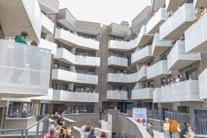 Vecinos asomados a los balcones durante la entrega de una promoción de vivienda protegida de alquiler de la EMV en Rivas