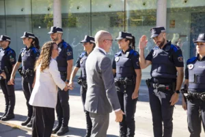 Un hombre vestido con un traje gris estrecha la mano a una fila de agentes de la policía local en Rivas.