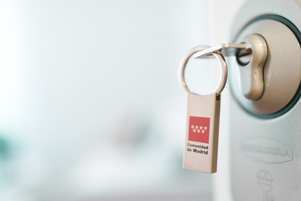 Detalle de una llave con el llavero de la Comunidad de Madrid en una cerradura