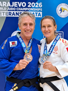 Ana Roldán y Paco Lorenzo, con los quimonos y las medallas de plata del Mundial máster de judo de Sarajevo, posan ante un panel del campeonato