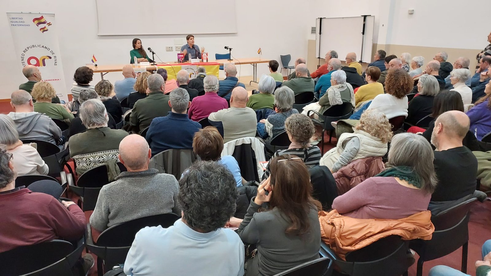 Público asistente a una asamblea del Ateneo Republicano de Rivas, con la pancarta de la entidad y banderas republicanas