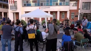 Un grupo de personas se sienta en sillas y tiendas de campaña en la plaza situada frente al ayuntamiento de Rivas-Vaciamadrid, como parte de una protesta en favor de la vivienda digna.