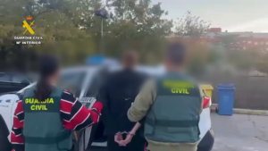 Dos agentes de la Guardia Civil conducen al detenido esposado hacia el coche patrulla en Rivas Vaciamadrid