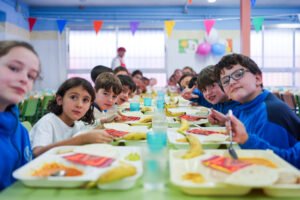 Niños y niñas almorzando en un comedor escolar