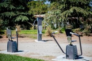 Área biosaludable con aparatos de ejercicio entre arbolado en el entorno del CEIPSO La Luna, una de las intervenciones del proyecto Renatura Rivas en el barrio Oeste