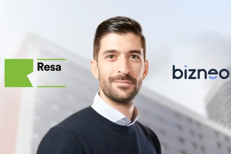 Un hombre con pelo oscuro corto y barba, vestido con un jersey oscuro sobre una camisa de cuello, de pie delante de edificios borrosos. Los logotipos de Resa y Bizneo HR, líderes en gestión de RR. HH. para residencias de estudiantes, son visibles a su lado.
