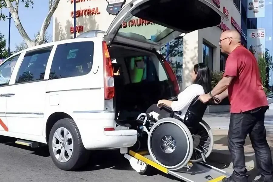 Un taxista ayuda a entrar en su vehículo a una cliente en silla de ruedas | Foto del Ayuntamiento de Madrid