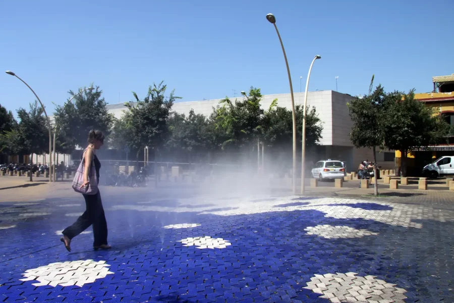 Una mujer cruza por una instalación de chorros de agua en una plaza | Foto de 123RF/fotovlad