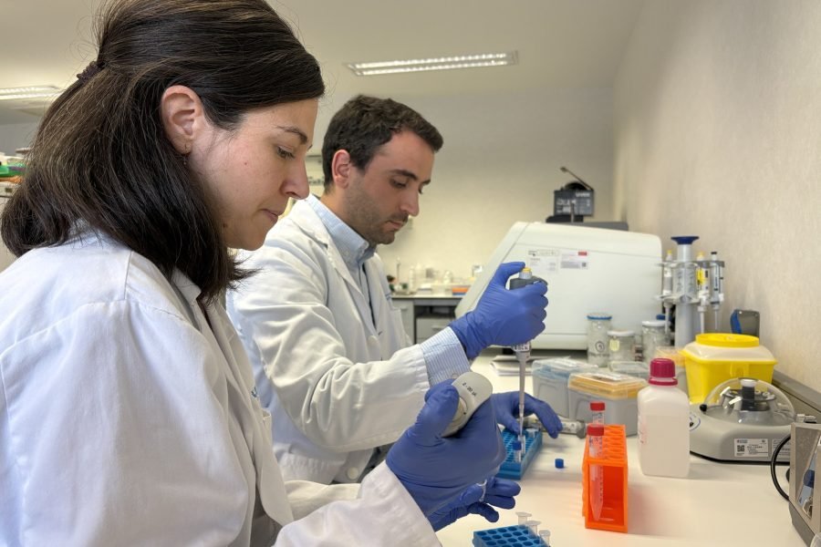 Dos personas con bata y guantes trabajando con micropipetas en un laboratorio