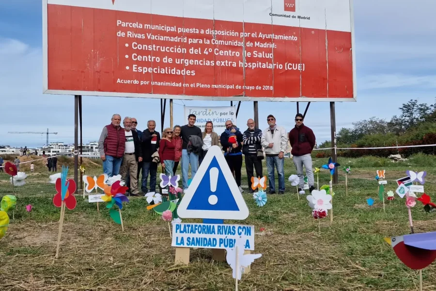 Un grupo de activistas de la Plataforma Rivas por la Sanidad Pública posan junto al cartel que anuncia el cuarto centro de salud.