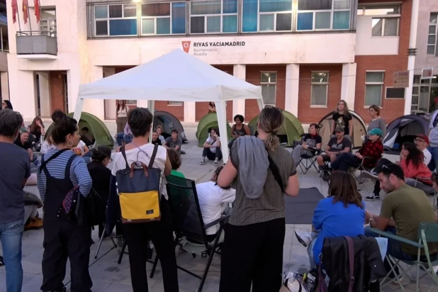 Un grupo de personas se sienta en sillas y tiendas de campaña en la plaza situada frente al ayuntamiento de Rivas-Vaciamadrid, como parte de una protesta en favor de la vivienda digna.
