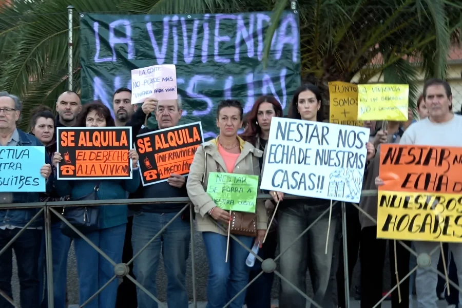 Un grupo de manifestantes se encuentra detrás de una valla metálica en la Ronda de Gloria Fuertes, con pancartas en las que se leen lemas contra los desahucios y los fondos buitre depredadores.