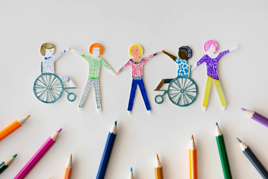 Un grupo de personas cogidas de la mano y un grupo de lápices de colores dispuestos cerca de un borrador automático.