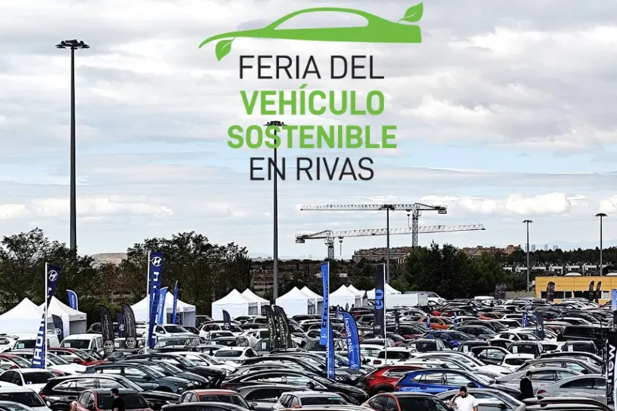 Una gran feria del automóvil al aire libre con filas de vehículos aparcados, carpas blancas y banderas del evento. El texto sobre la imagen dice "Feria del Vehículo Sostenible de Rivas" con un icono de un coche verde sobre el texto.