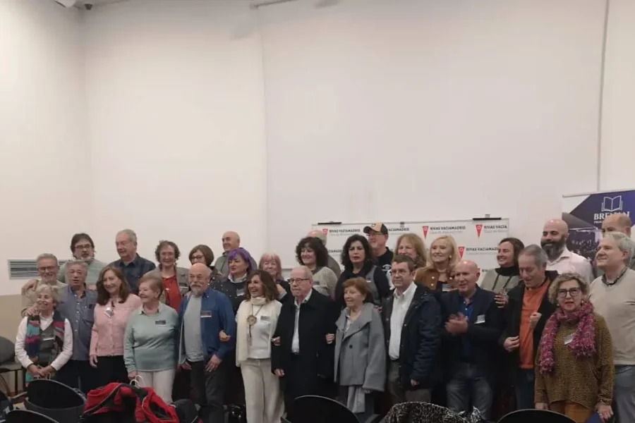 Un grupo de unos 30 adultos, hombres y mujeres, posan juntos en varias filas dentro de una sala con paredes blancas durante el Encuentro de Poetas en Red en Rivas. Al fondo se ven pancartas y sillas vacías.