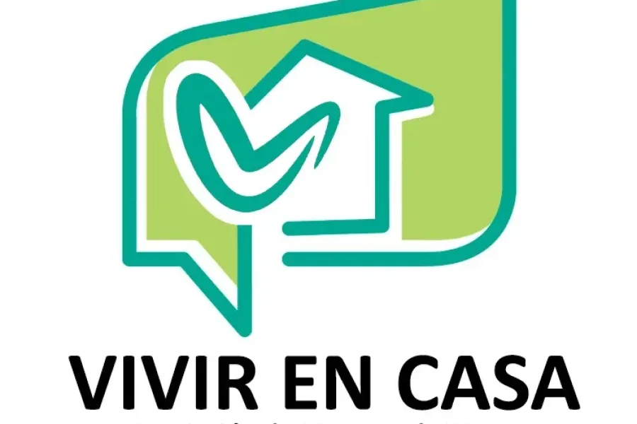 Un logotipo en tonos verde y verde azulado con una casa dentro de un bocadillo, que presenta un diseño en forma de marca de verificación. Debajo, un texto en negro reza «VIVIR EN CASA Asociación de Mayores de Rivas», lo que pone de relieve el compromiso de la asociación con las personas mayores de Rivas.