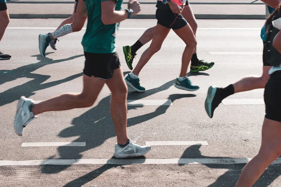 Varios corredores, vestidos con ropa deportiva, corren por una carretera asfaltada durante la Carrera por la Biodiversidad.